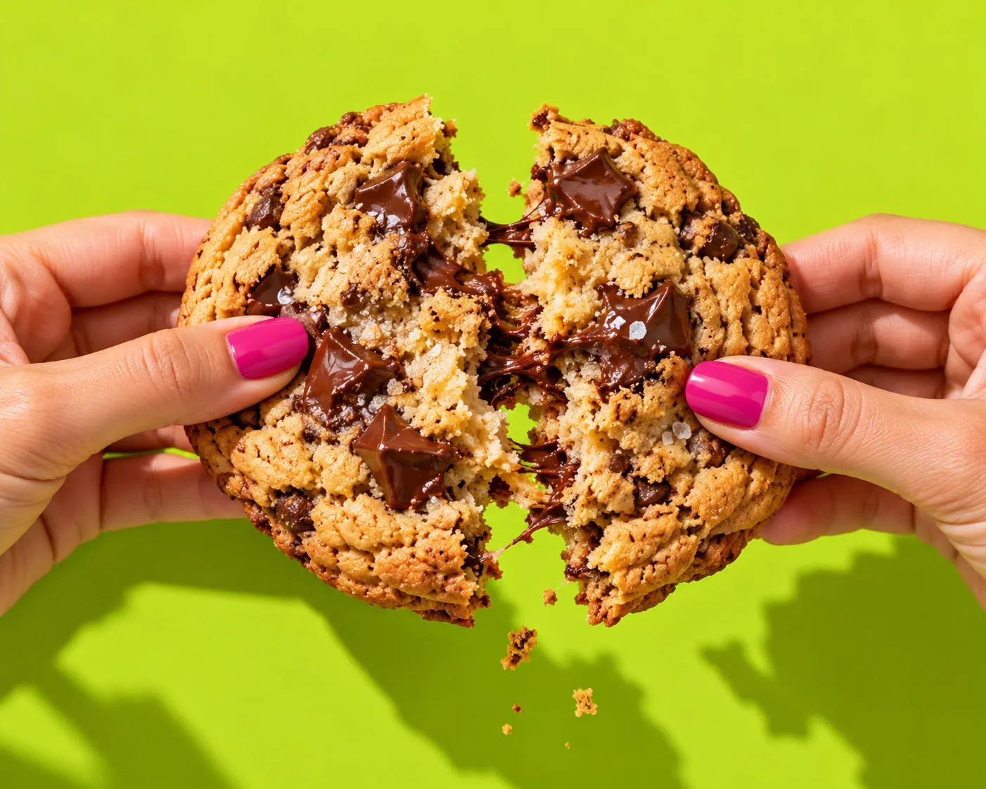Two hands pulling apart a warm chocolate chunk cookie