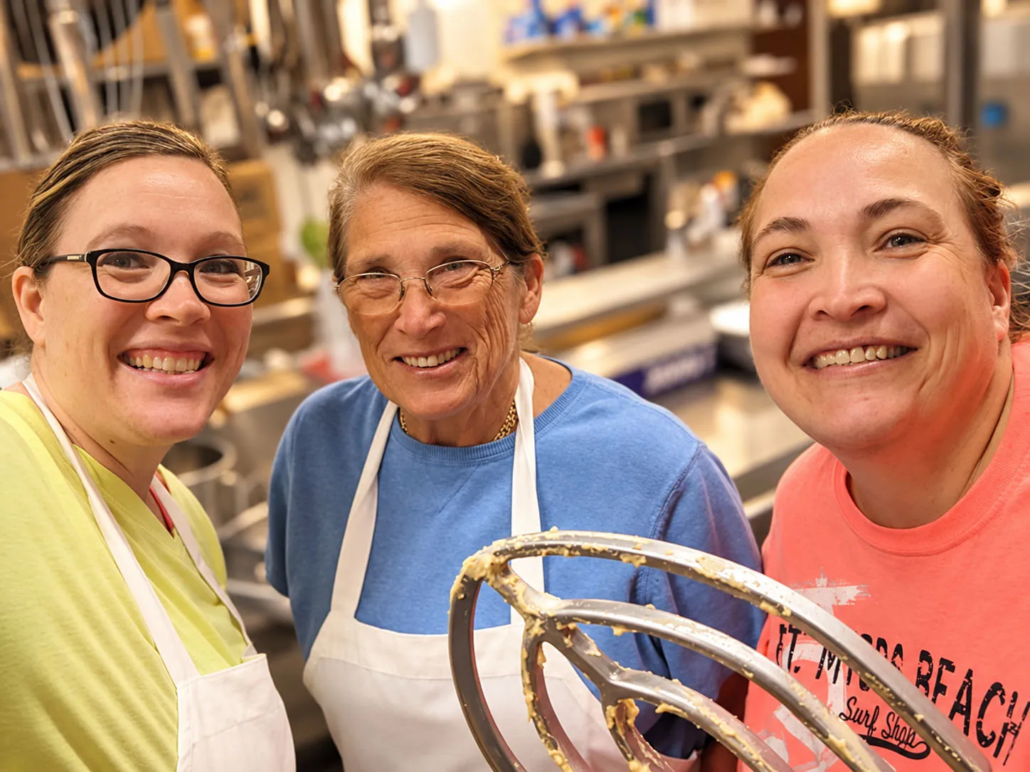 Emily Raffel and her daughters holding up a dough-covered mixer paddle